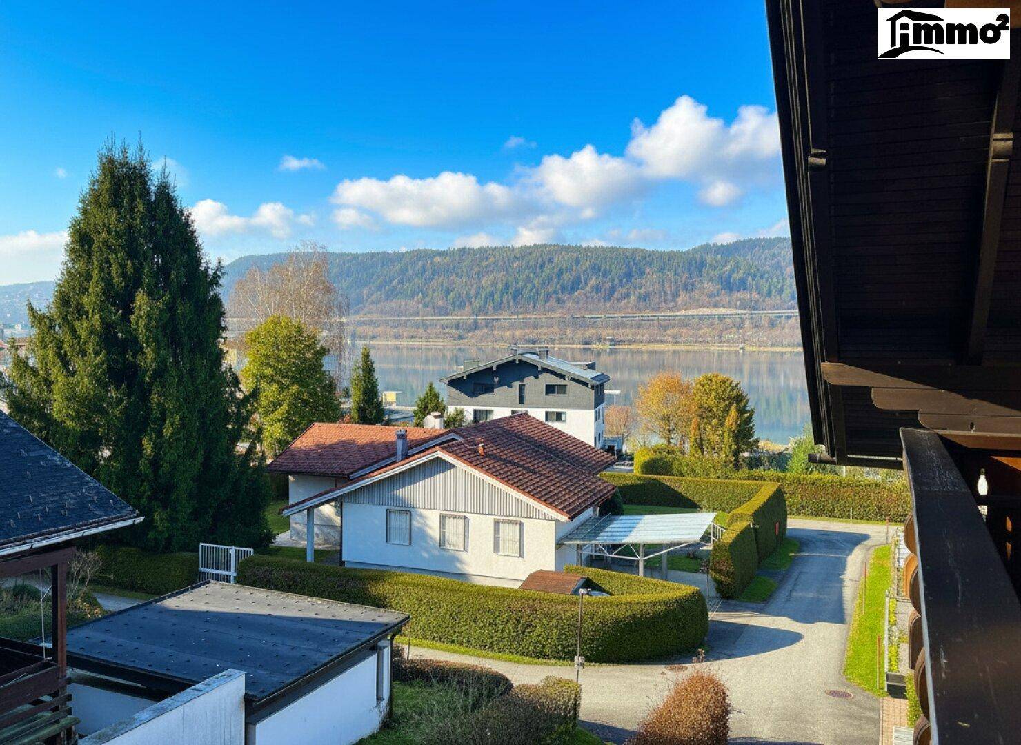 Malerischer Ausblick auf den See und die umliegende Landschaft mit weiteren Häusern und Bäumen.