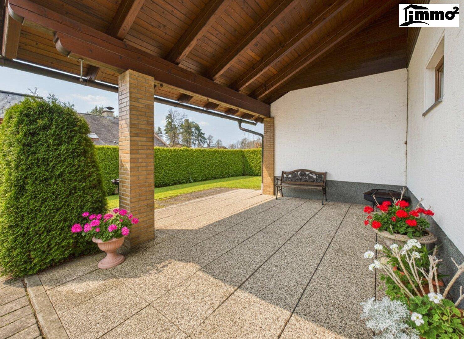 Überdachte Terrasse mit Sitzbank und Blick ins Grüne, ideal für entspannte Stunden im Freien.