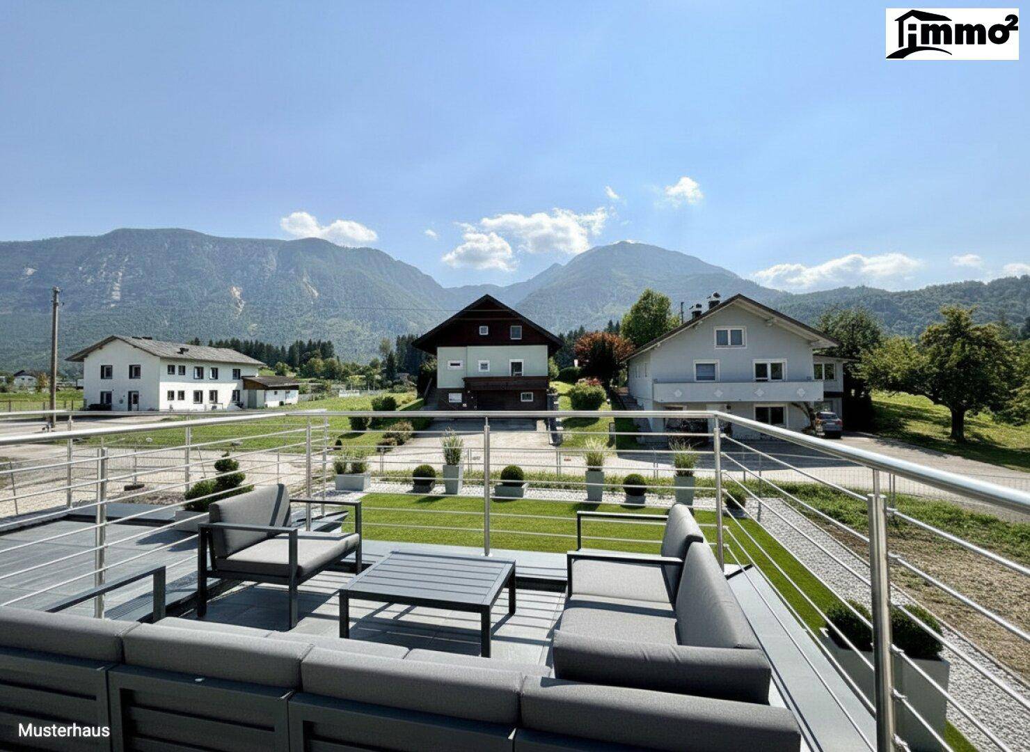 Geräumige Dachterrasse mit moderner Lounge-Möblierung und weitem Bergblick unter blauem Himmel.