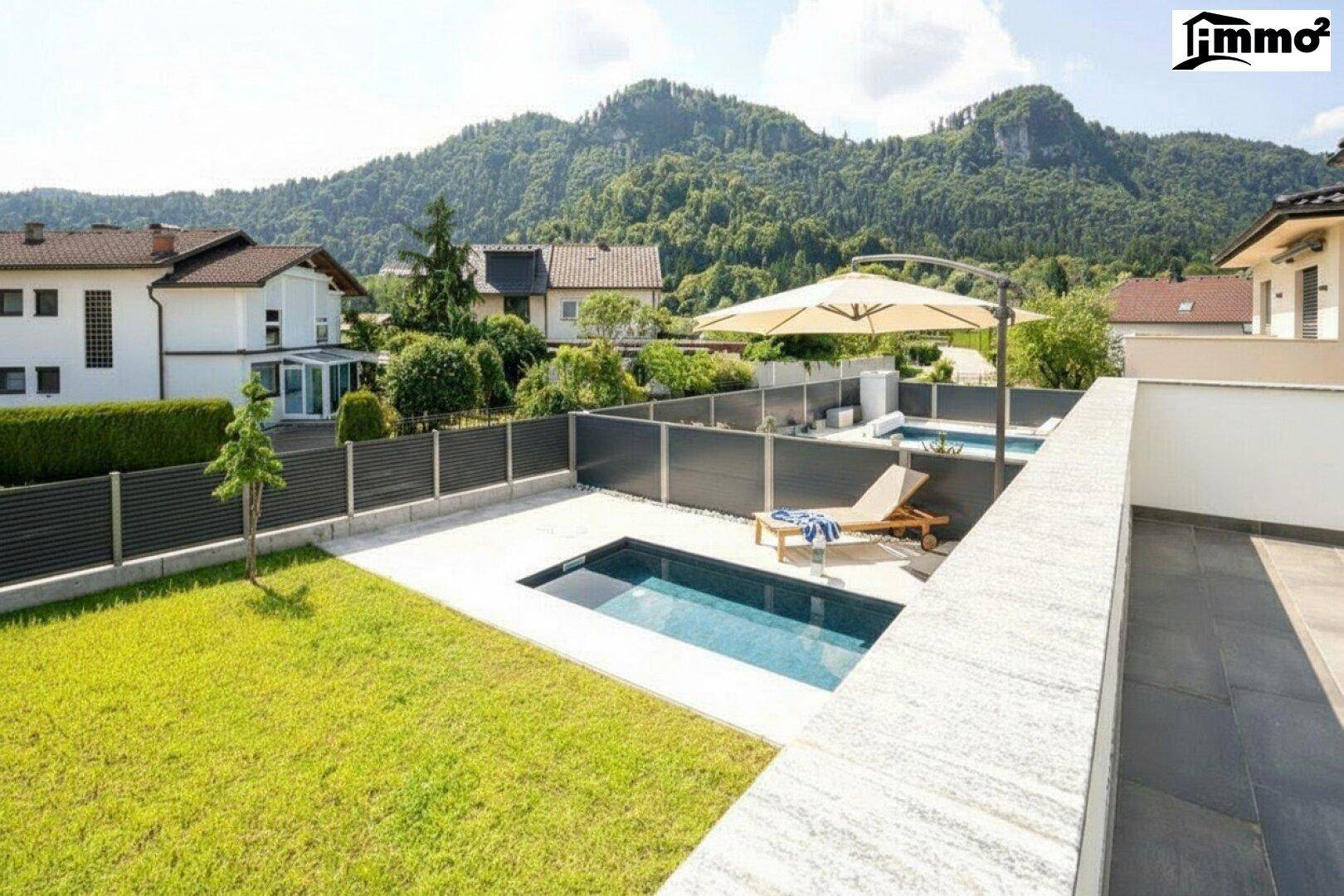 Großer Garten mit Pool, Liegebereich und Bergblick, umgeben von einer modernen Zaunanlage.