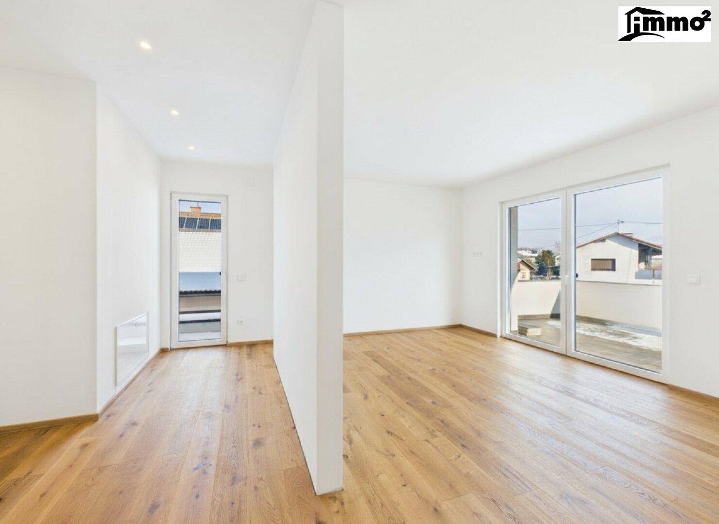 Helles, leeres Zimmer mit Holzboden und Fenstertür zum Balkon, ideal für ein Büro.