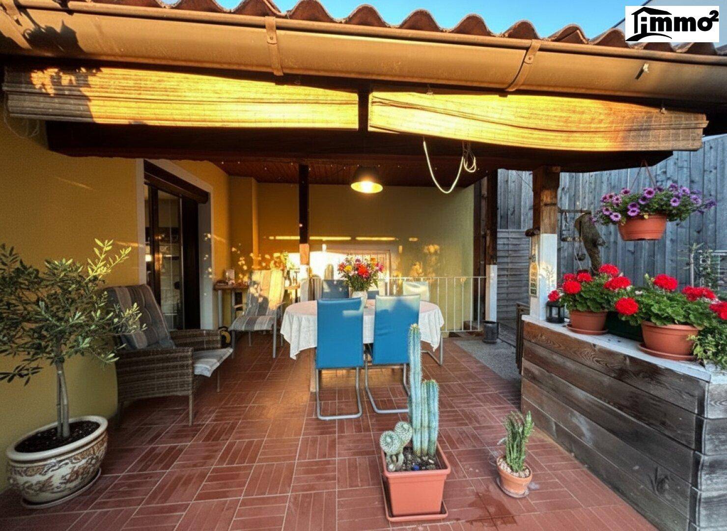 Einladende überdachte Terrasse mit Esstisch und Pflanzen in Töpfen.
