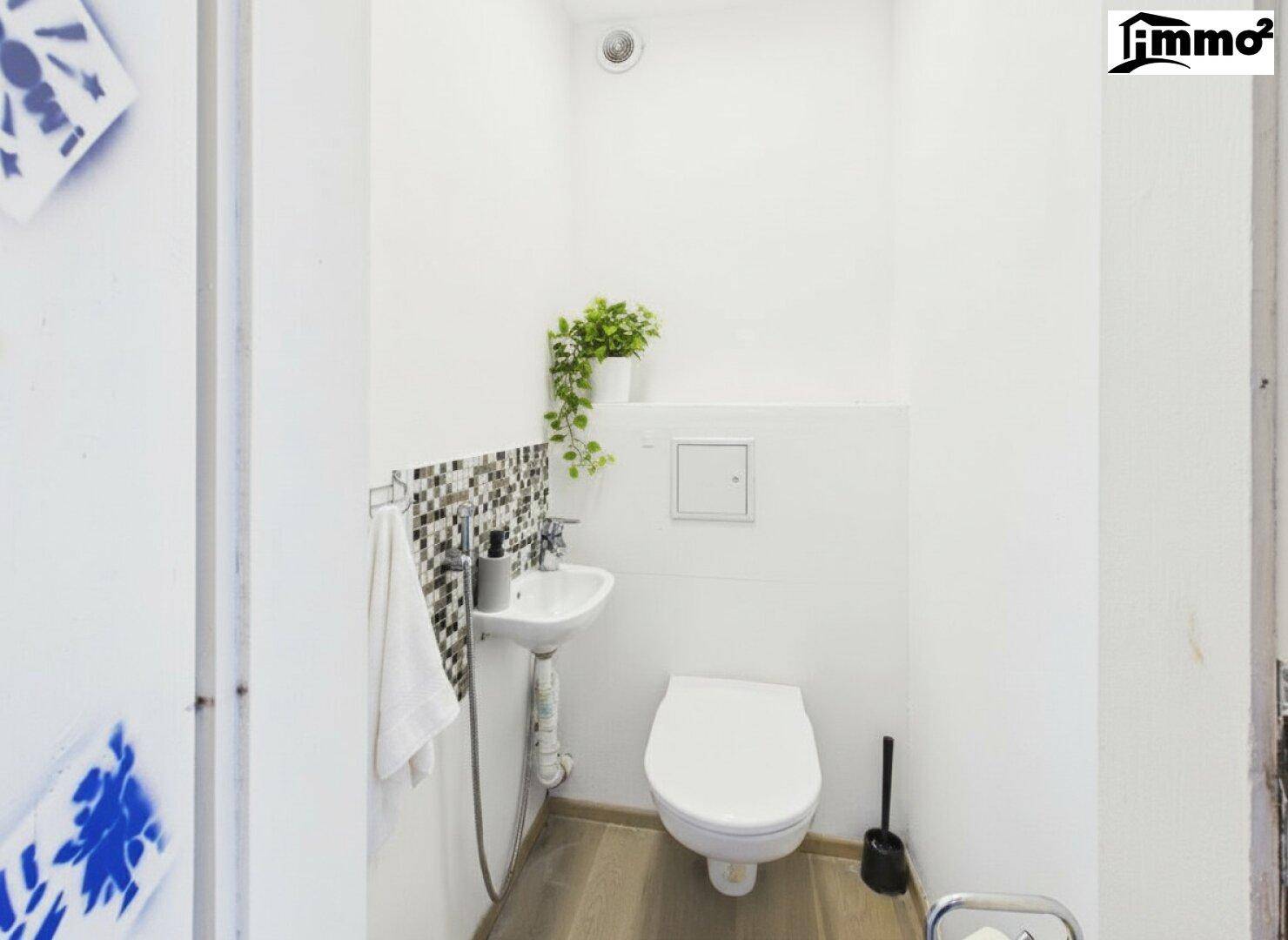 Kleines Gäste-WC mit Wand-WC, Waschbecken und Mosaikfliesen.