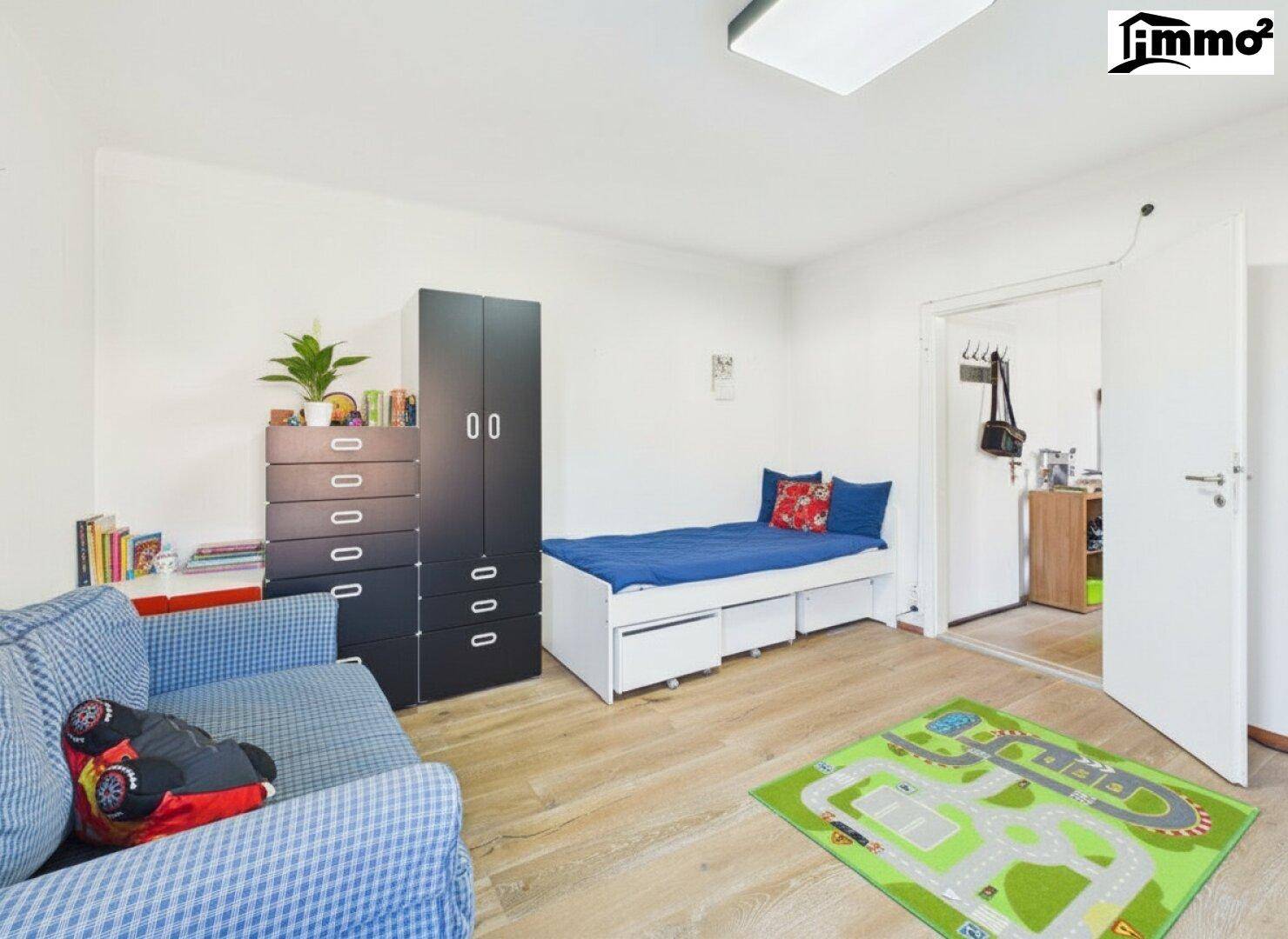 Helles Kinderzimmer mit Bett, Schrank und Sofa.