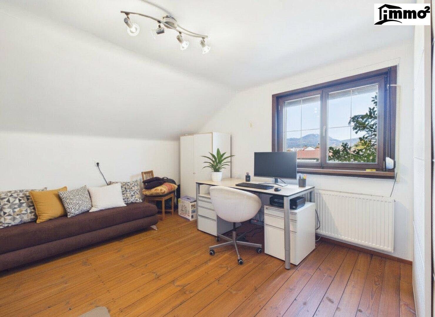 Arbeitszimmer im Dachgeschoss mit Holzboden, Schreibtisch und Sofa.