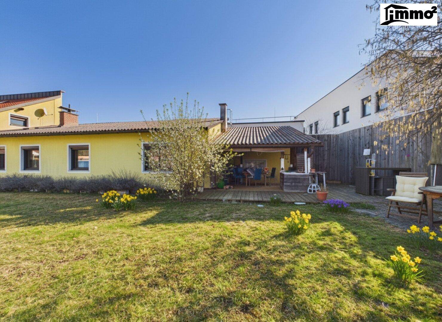 Überdachte Terrasse mit Essbereich und Zugang zum grünen Garten.