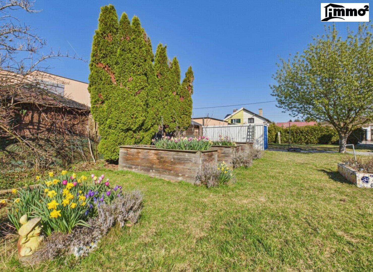 Gepflegter Gartenbereich mit Hochbeeten und blühenden Pflanzen.