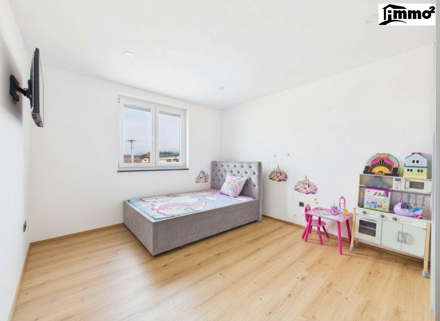 Kinderzimmer mit Einzelbett, Holzboden und spielerischer Dekoration an der Wand.