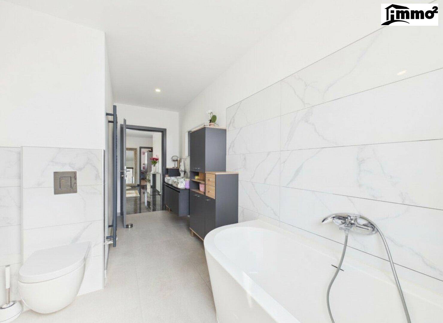 Geräumiges Badezimmer mit Badewanne, wandhängendem WC und modernen Fliesen.