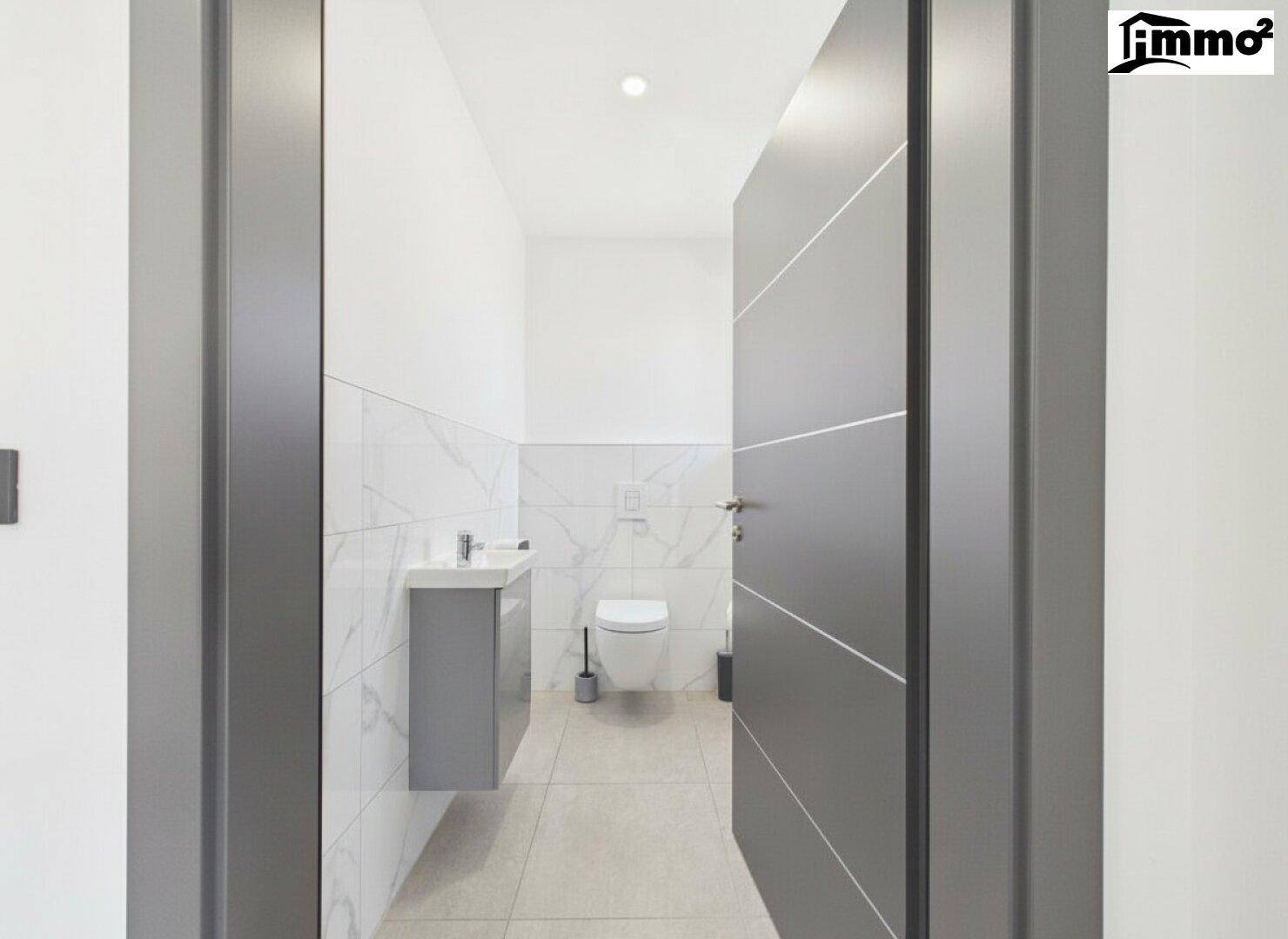 Modernes Gäste-WC mit wandhängendem WC, kleinem Waschbecken und eleganten Fliesen.