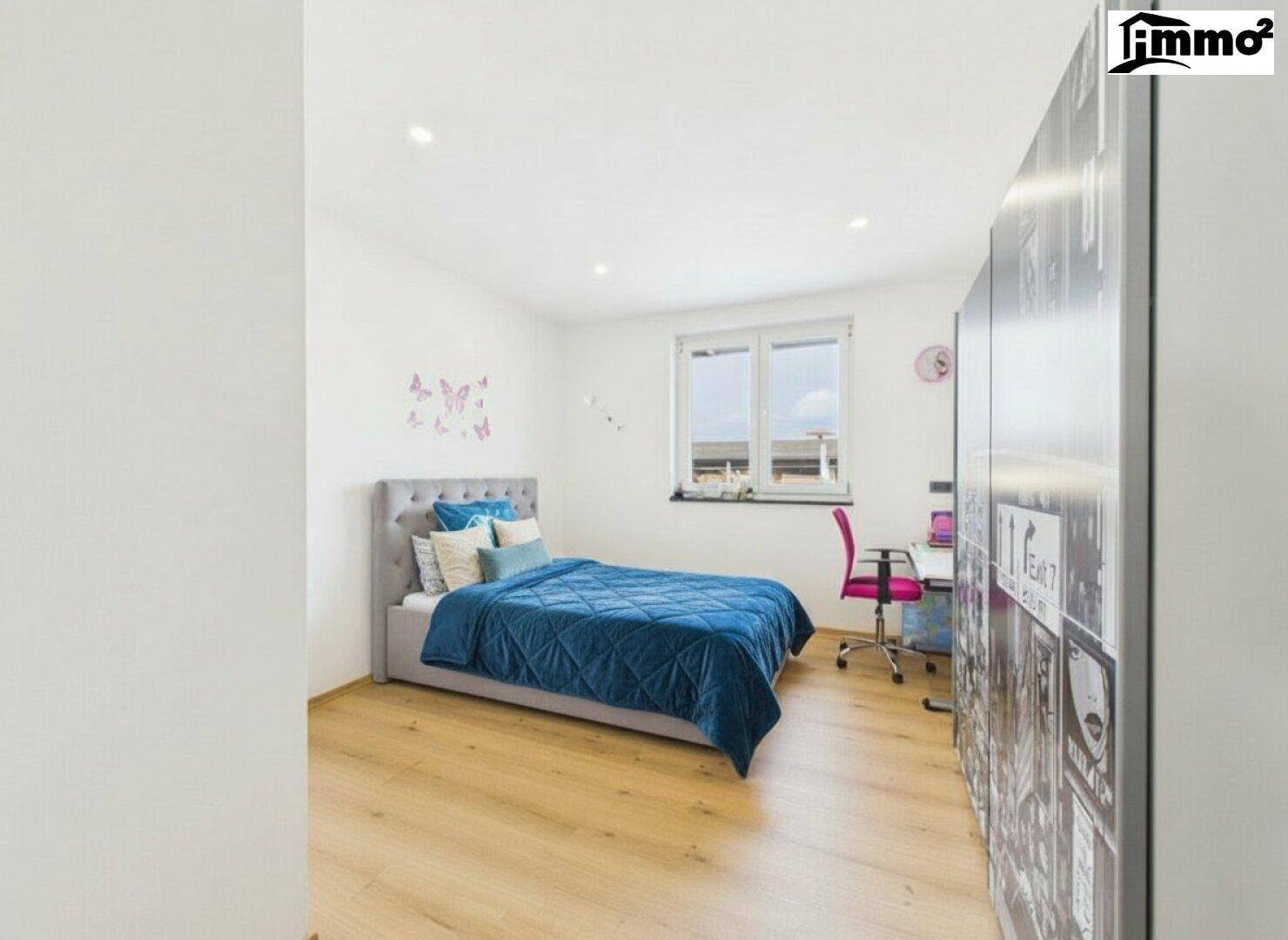 Kinderzimmer mit Einzelbett, Holzboden und Schreibtisch am Fenster.