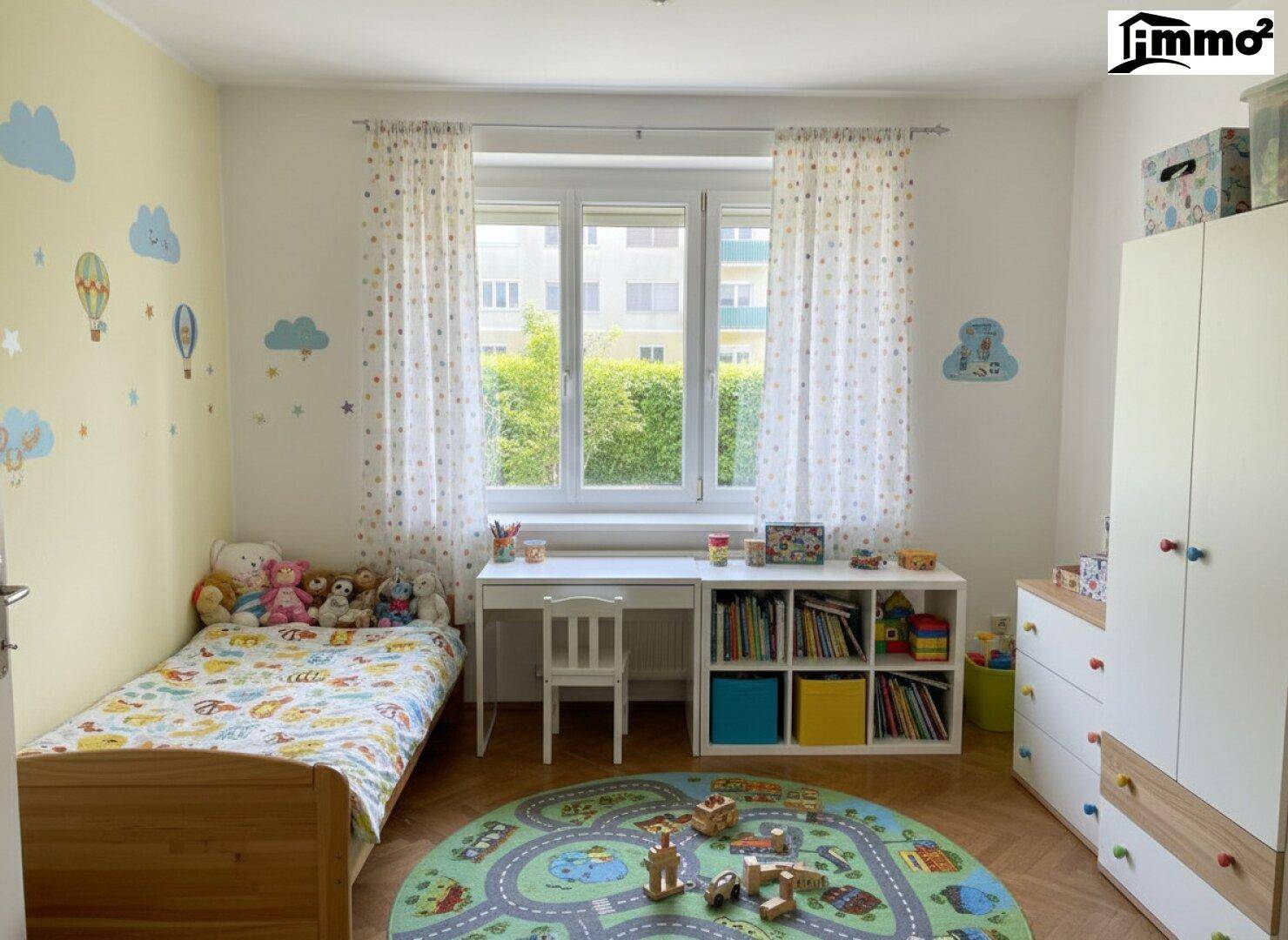Farbenfrohes Kinderzimmer mit Holzboden, Schreibtisch und spielerischer Wanddekoration.