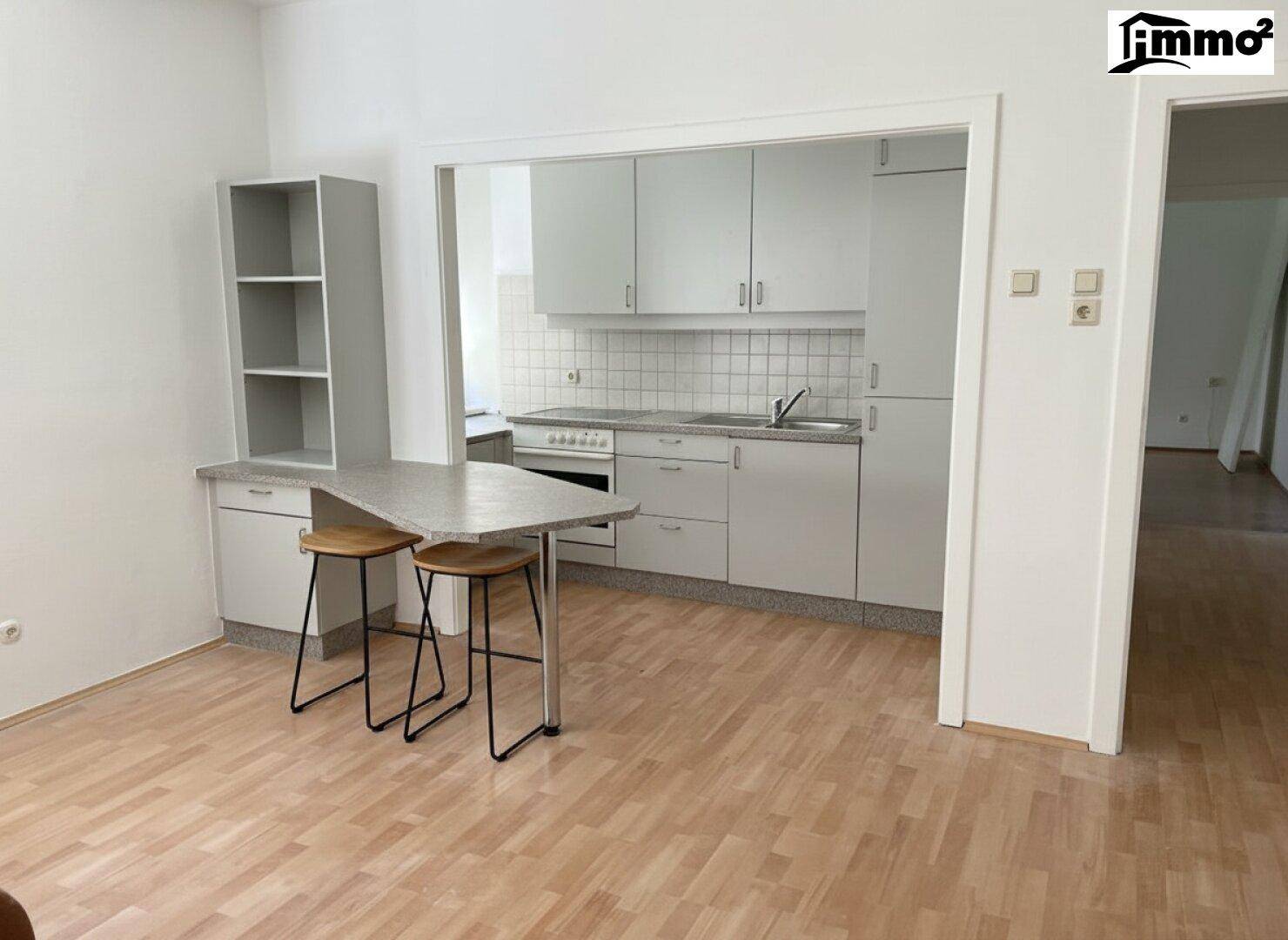 Kleine Küche mit grauen Schränken, Frühstücksbar und Laminatboden.