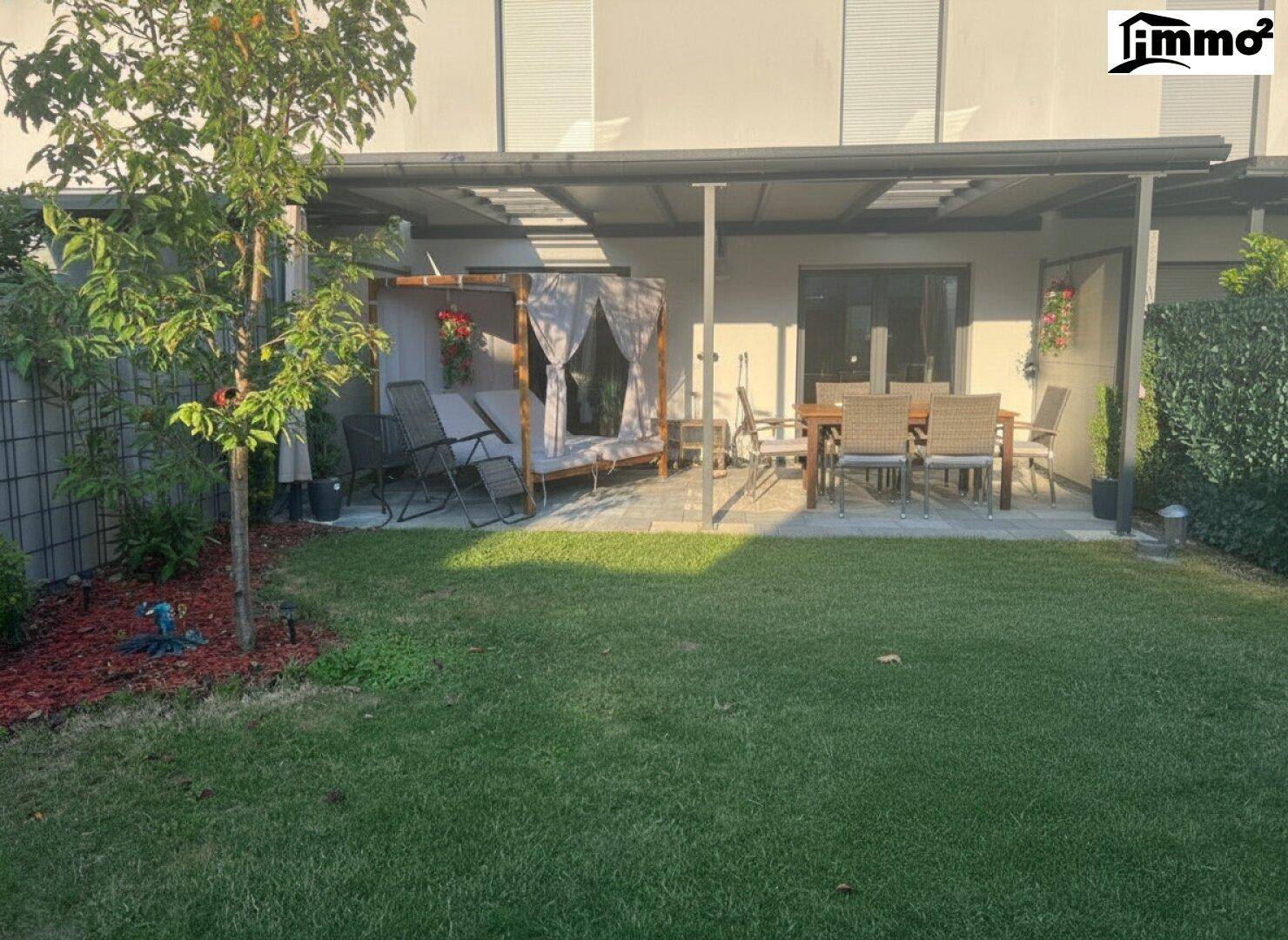 Großer, gepflegter Garten mit Rasenfläche und überdachter Terrasse für Mahlzeiten im Freien.