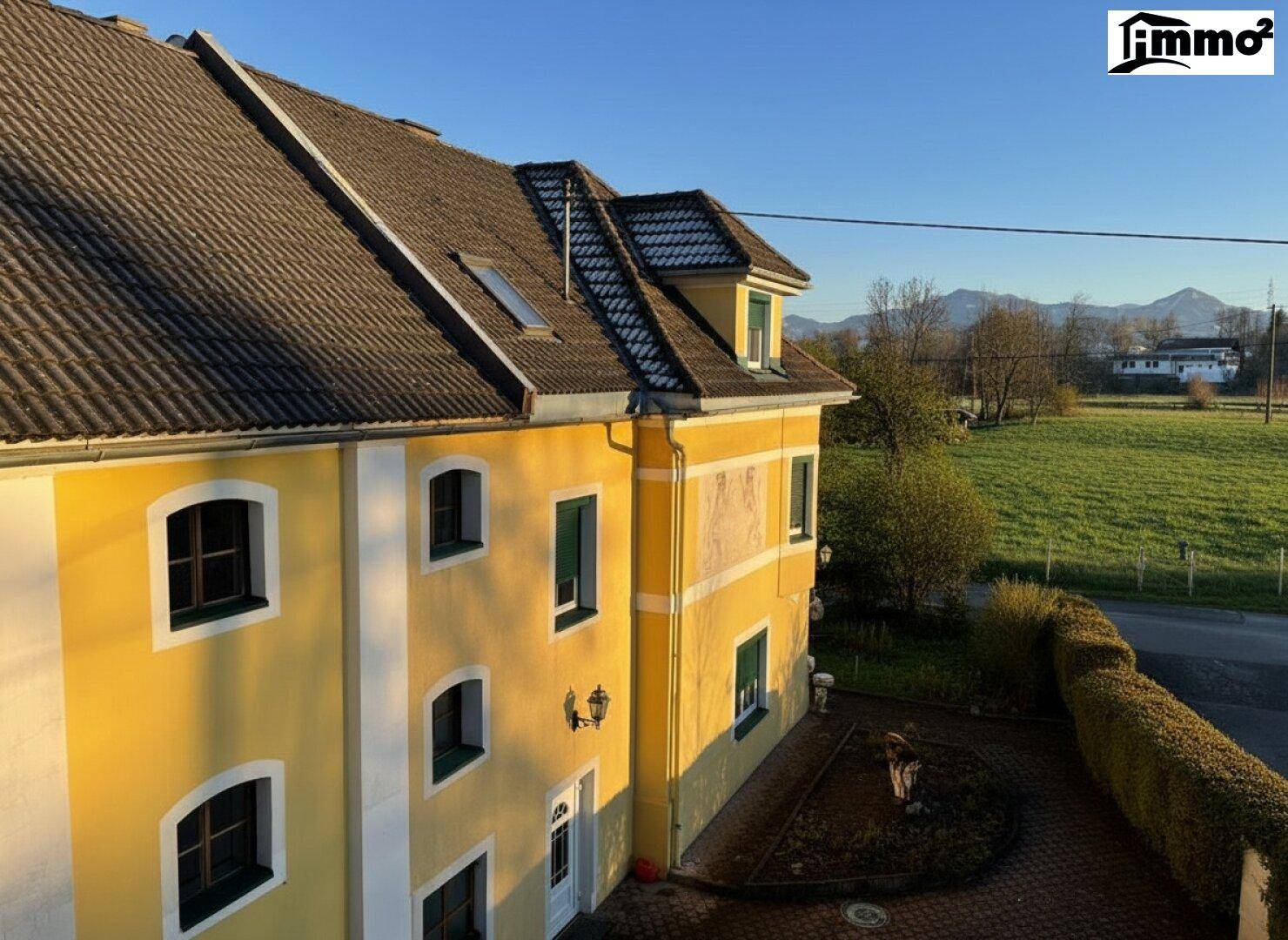 Seitenansicht des Gebäudes mit Ziegeldach und Blick auf die umliegende grüne Landschaft.
