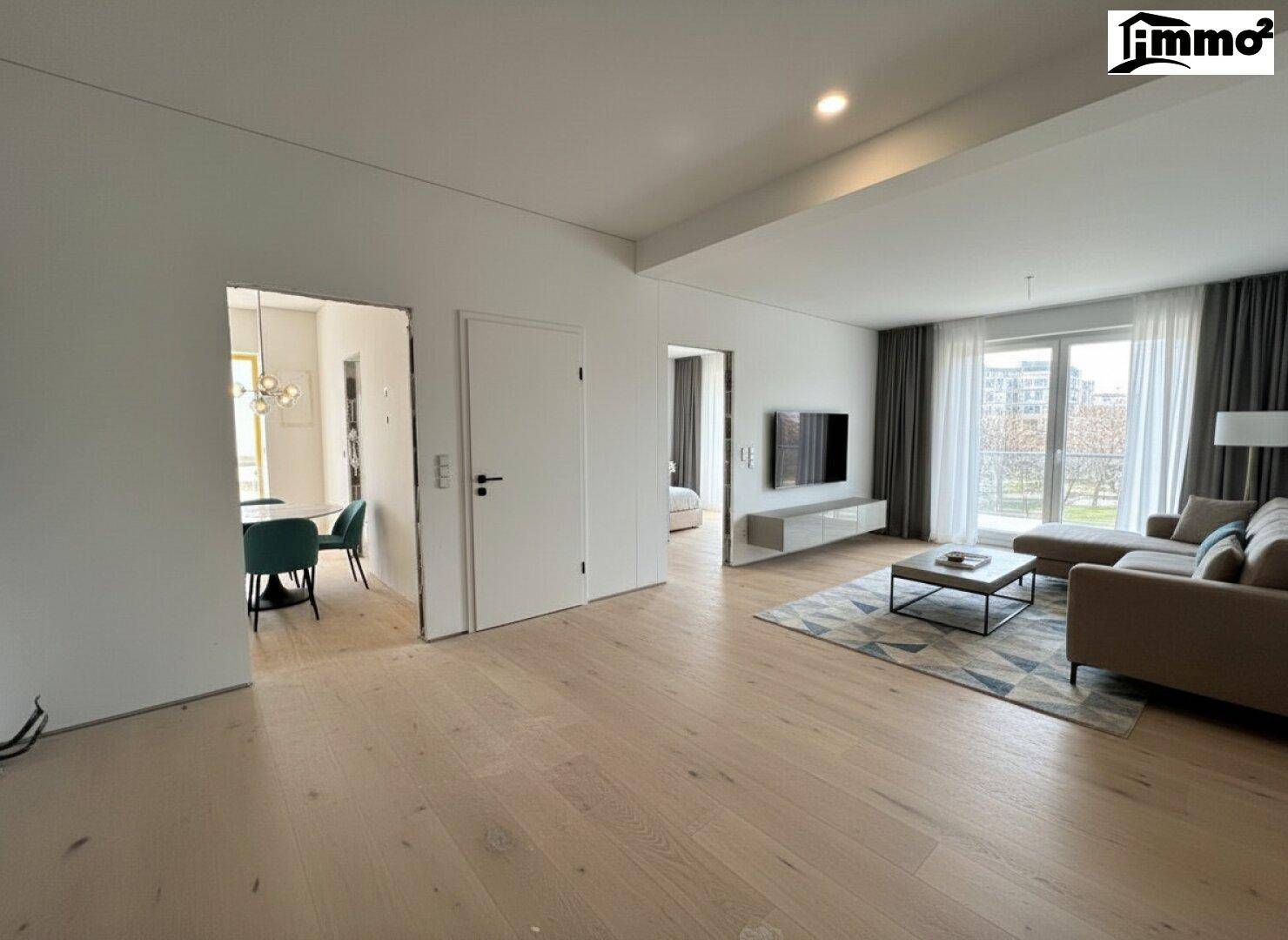 Helles Wohnzimmer mit modernem Parkettboden, beiger Couch und Zugang zum Essbereich.