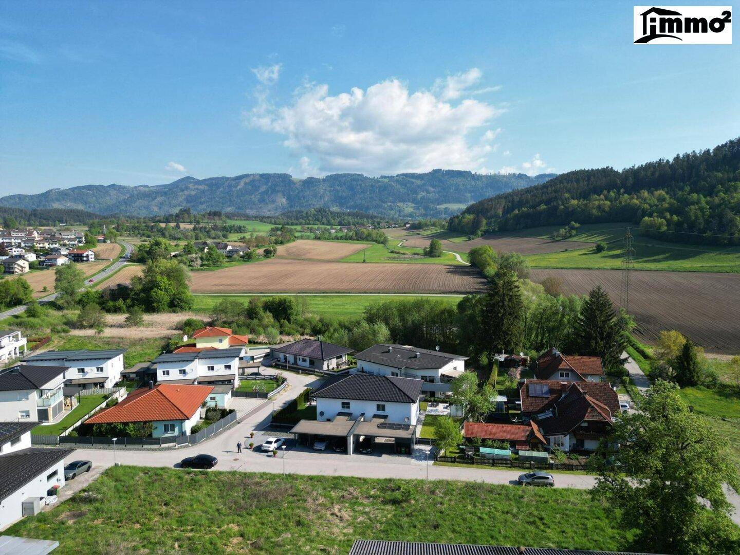 Weitläufige Luftaufnahme eines Grundstücks mit umliegenden Wohnhäusern und malerischem Bergblick.