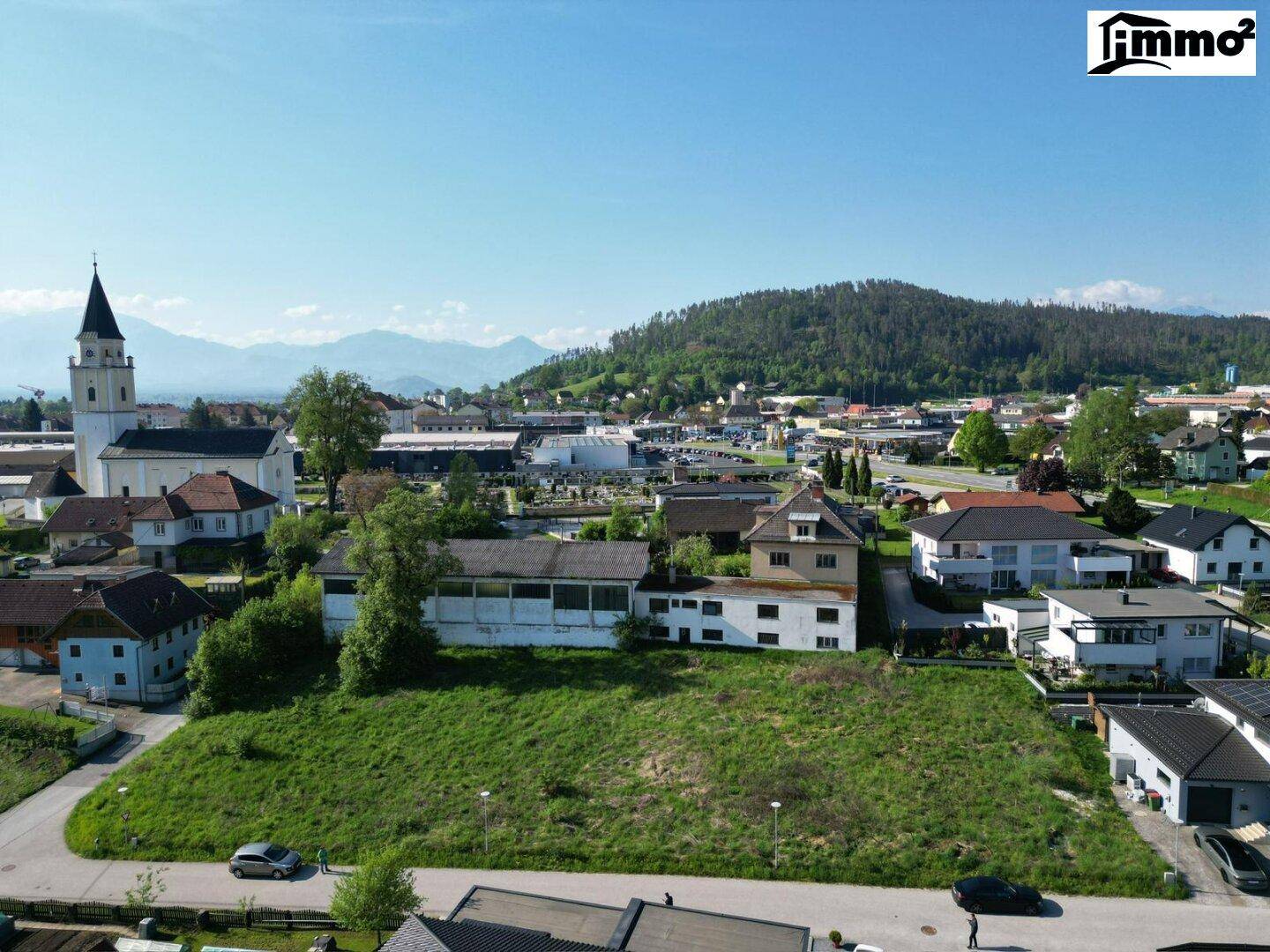 Luftaufnahme eines Baugrundstücks in Stadtnähe mit Blick auf eine Kirche und die umliegende Bebauung.