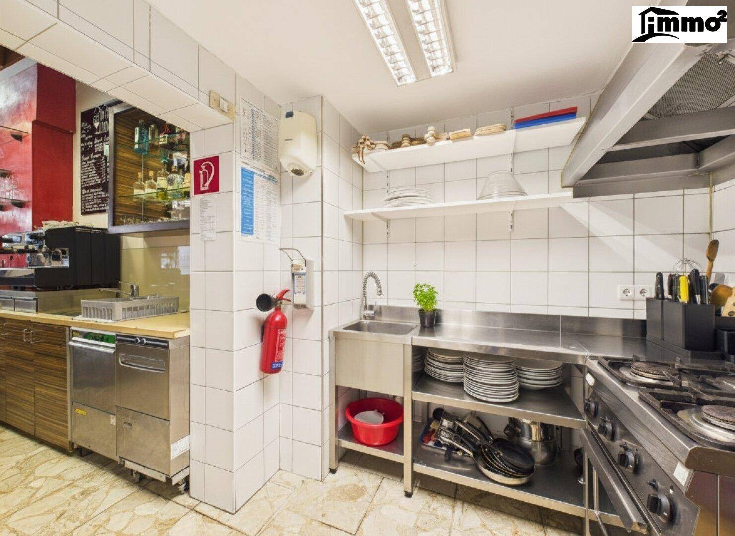 Gewerbliche Küche mit Fliesenwänden, Edelstahlspüle und Feuerlöscher.