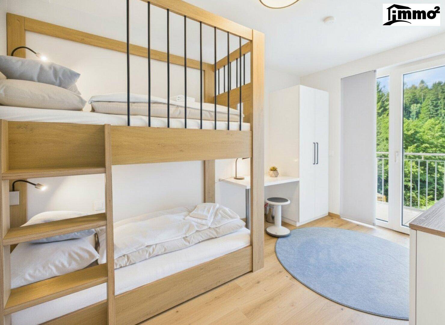 Helles Kinderzimmer mit Etagenbett und direktem Zugang zu einem Balkon mit Waldblick.