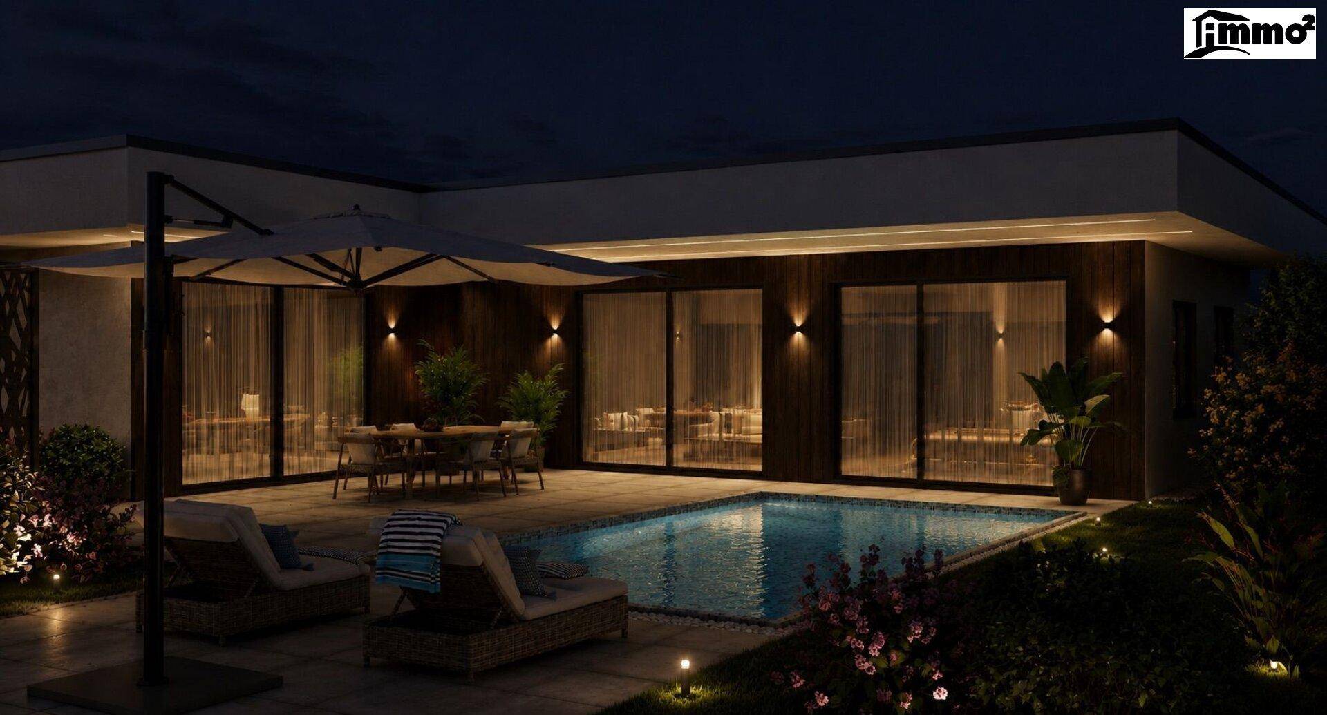 Beleuchteter Außenbereich bei Nacht mit Pool, Essbereich und Liegestühlen.
