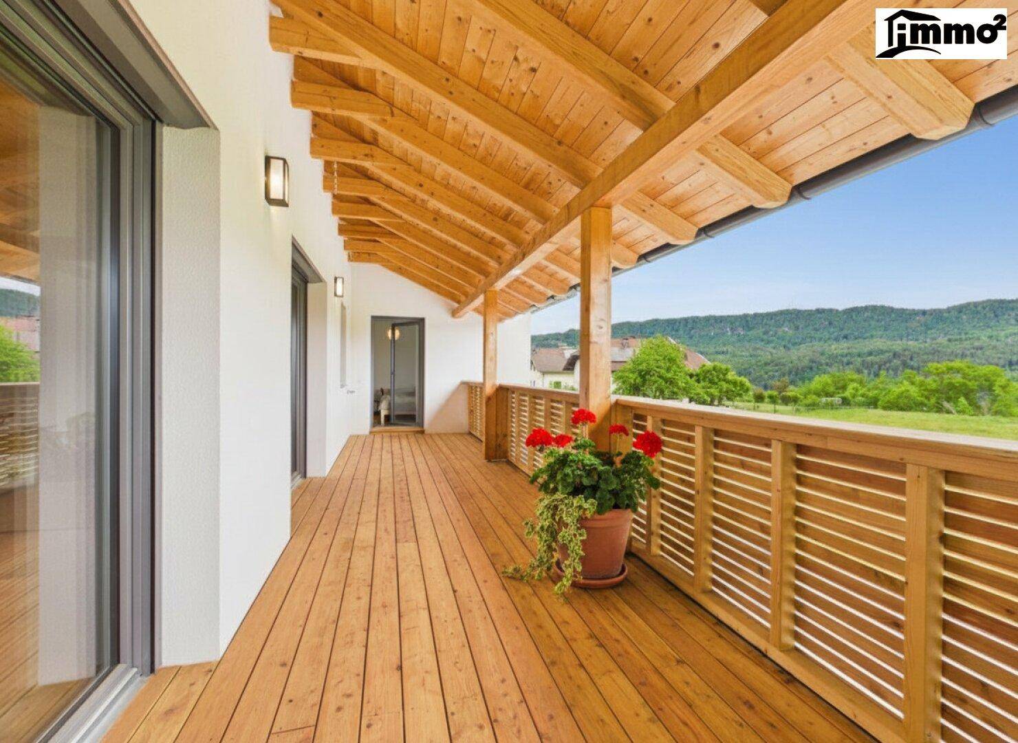 Geräumiger Holzbalkon mit schöner Aussicht auf die umliegende Landschaft und Berge.