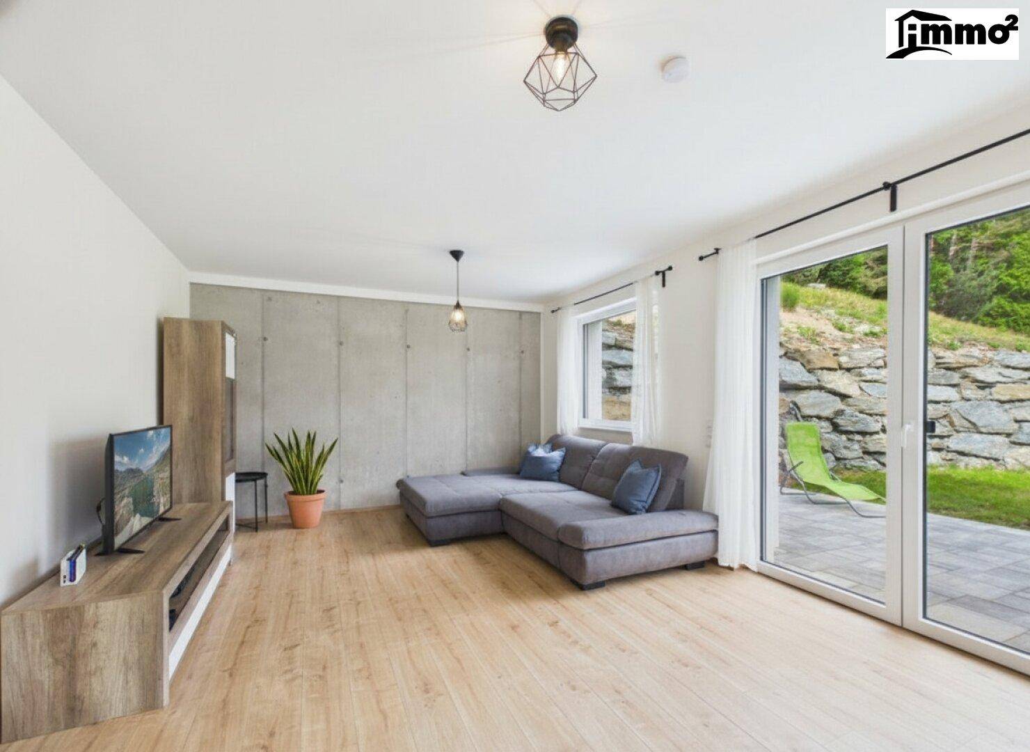 Gemütliches Wohnzimmer mit Holzboden, Ecksofa und Zugang zur Terrasse.