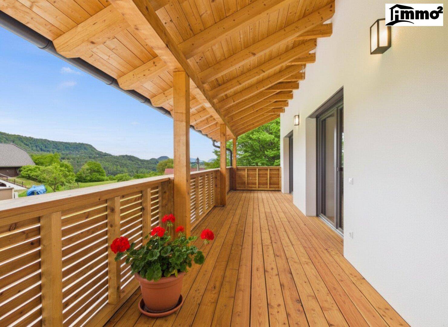 Langer Holzbalkon mit schöner Aussicht auf die umliegende Natur und Berge.