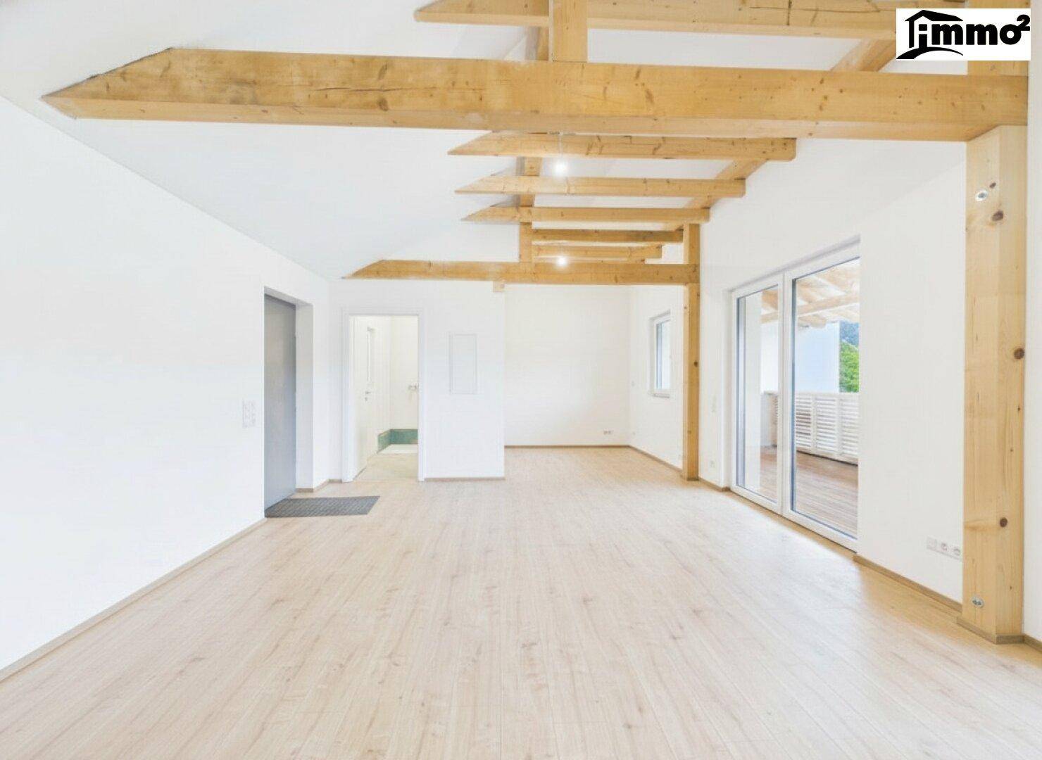 Geräumiger, unmöblierter Raum mit Holzbalken und Zugang zum Balkon.