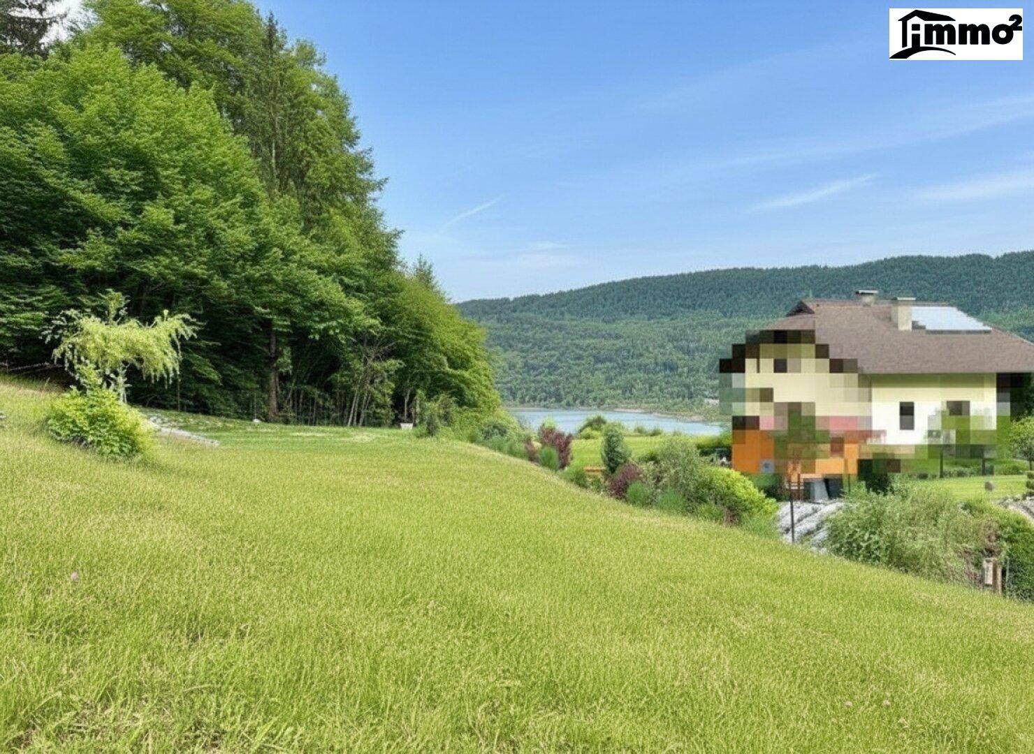 Weitläufige Grünfläche mit Blick auf einen See und bewaldete Hügel in der Ferne.