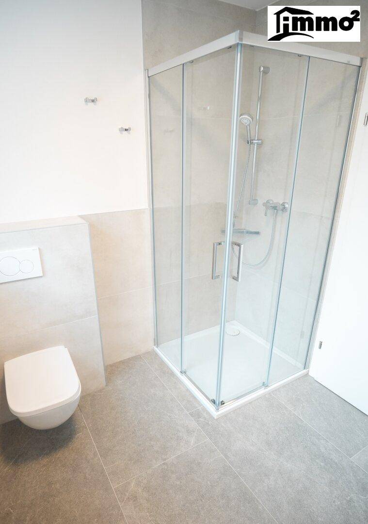 Modernes Badezimmer mit Duschkabine aus Glas und wandhängendem WC.