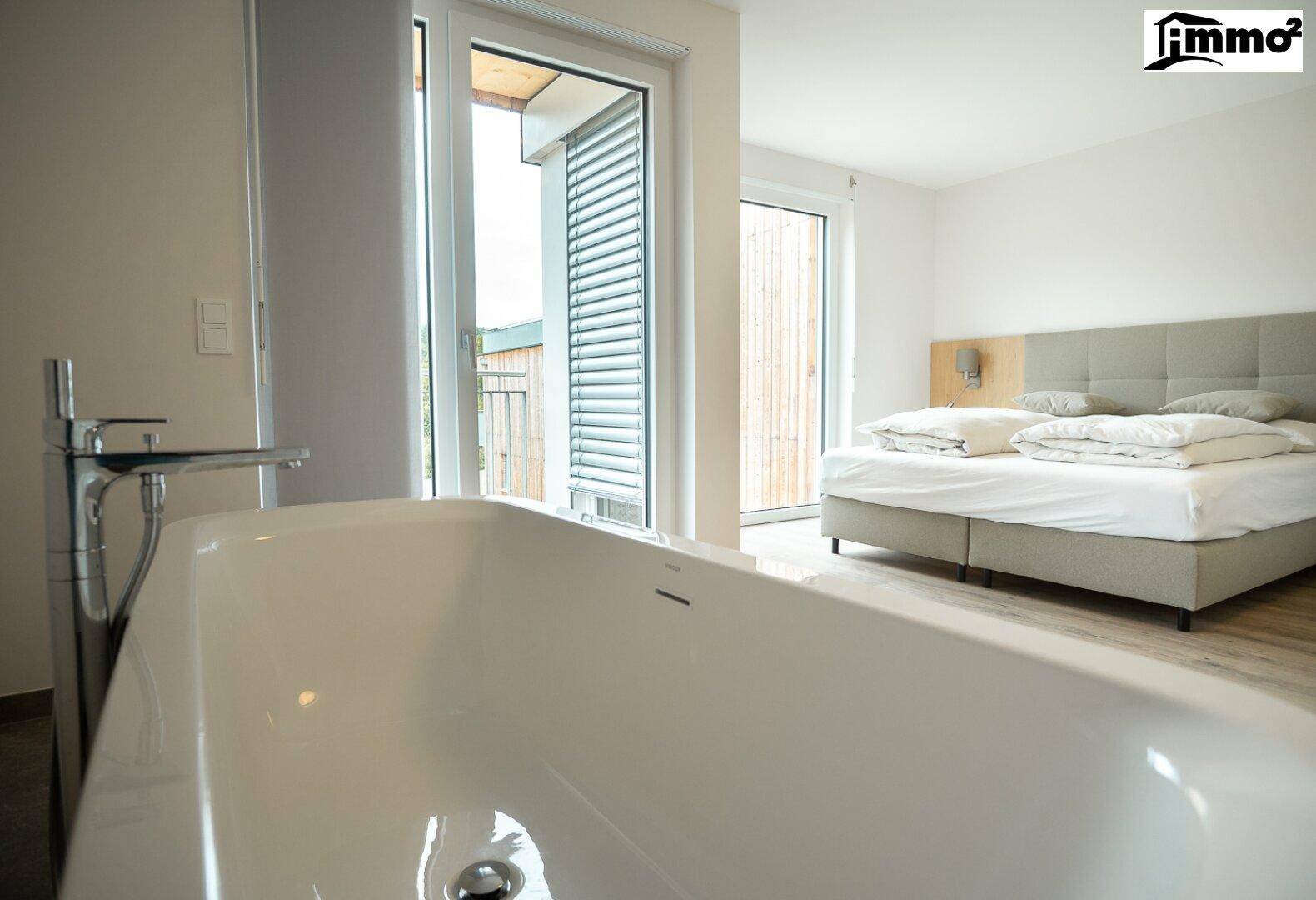 Helles Schlafzimmer mit freistehender Badewanne und Zugang zu einem Balkon oder einer Terrasse.