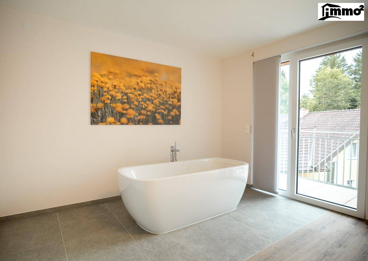 Geräumiges Schlafzimmer mit freistehender Badewanne und großem Fenster mit Blick nach draußen.