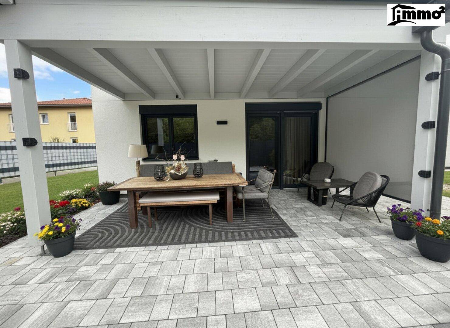 Überdachte Terrasse mit Sitzgelegenheiten und Blick auf den Garten.