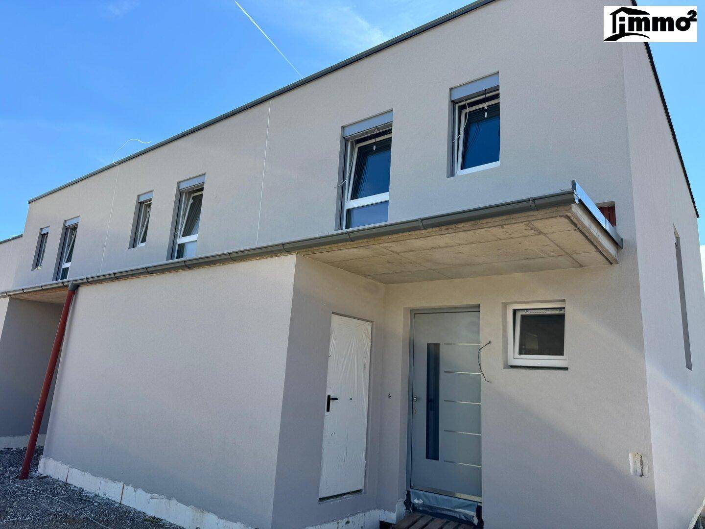 Eingangsbereich eines modernen Reihenhauses im Rohbauzustand mit großen Fenstern.