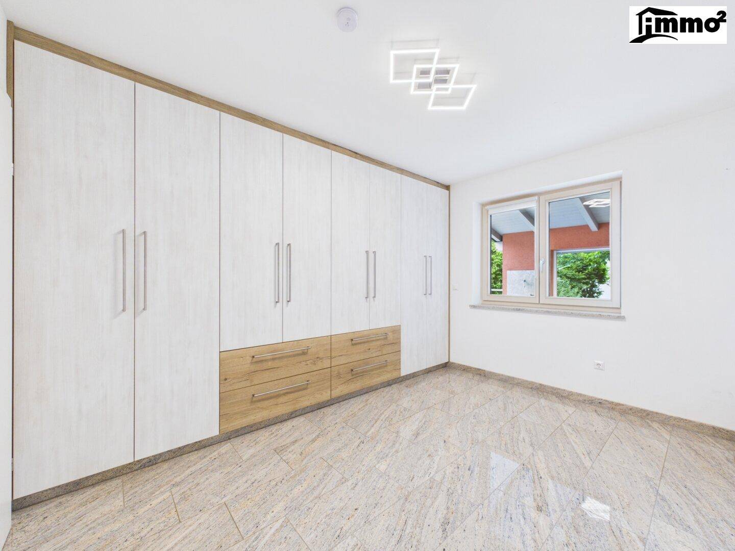Geräumiger Raum mit großen, modernen Einbauschränken und hellem Fliesenboden, ideal als Ankleidezimmer.