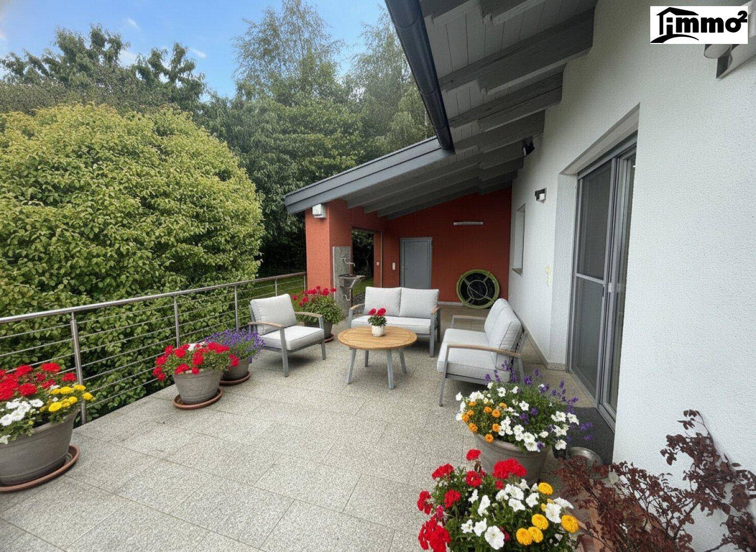 Geräumige Terrasse mit modernen Gartenmöbeln und bunten Blumen in Töpfen, ideal zum Entspannen.