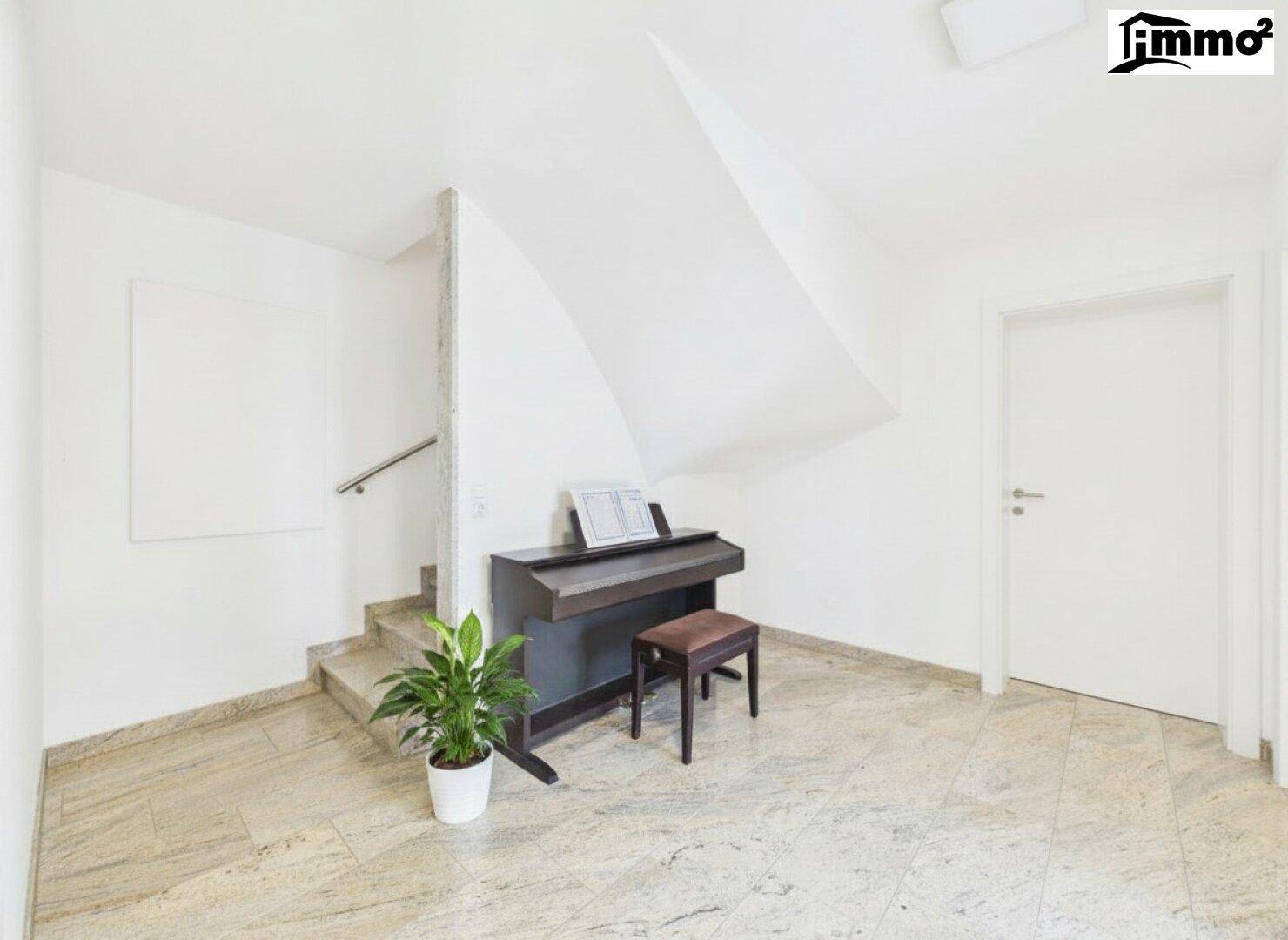 Heller Flurbereich mit Treppenaufgang und einem Klavier, das zum Musizieren einlädt.