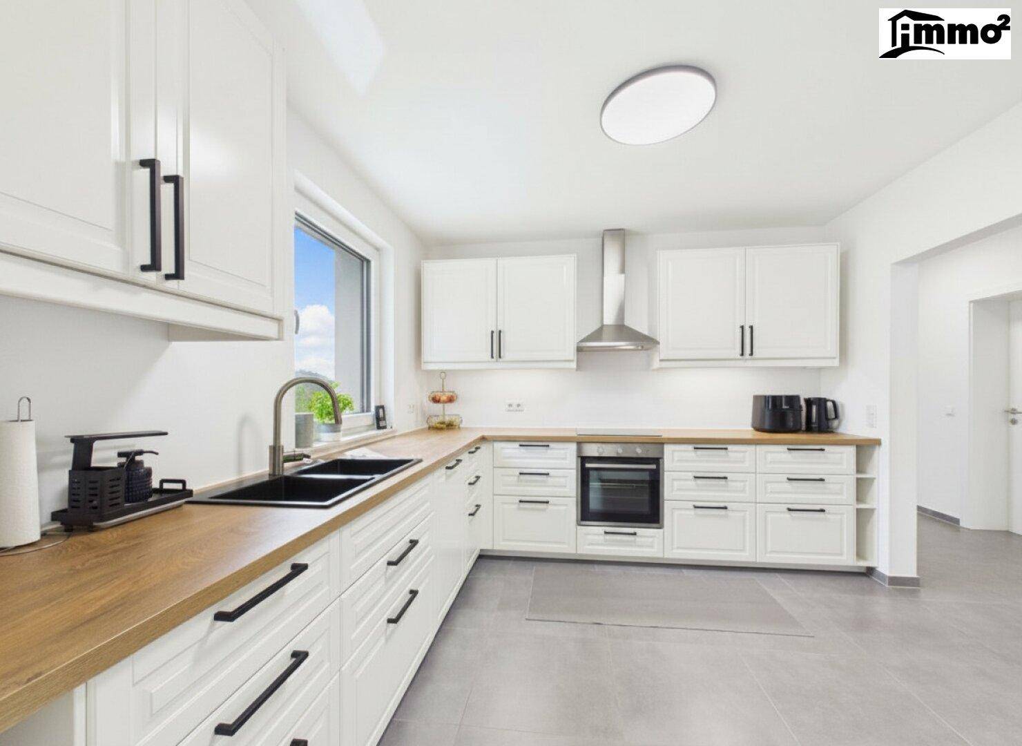 Helle, moderne Küche mit weißen Schränken, Holz-Arbeitsplatten und Fliesenboden.