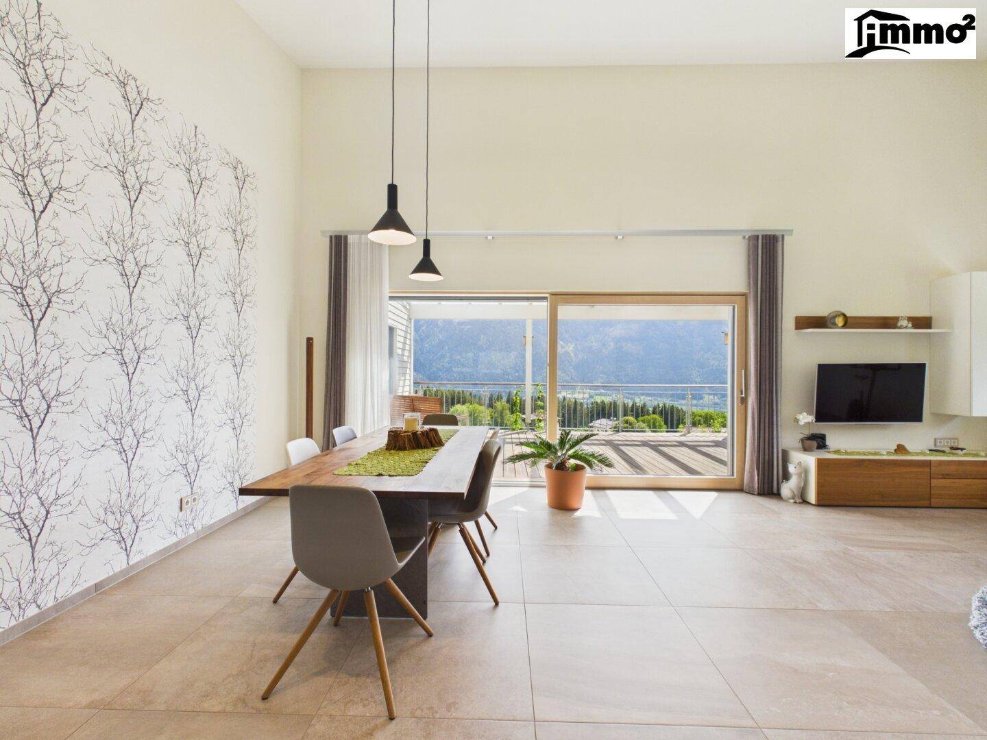 Heller Essbereich mit großem Holztisch, modernen Stühlen und Zugang zur Terrasse mit Bergblick.
