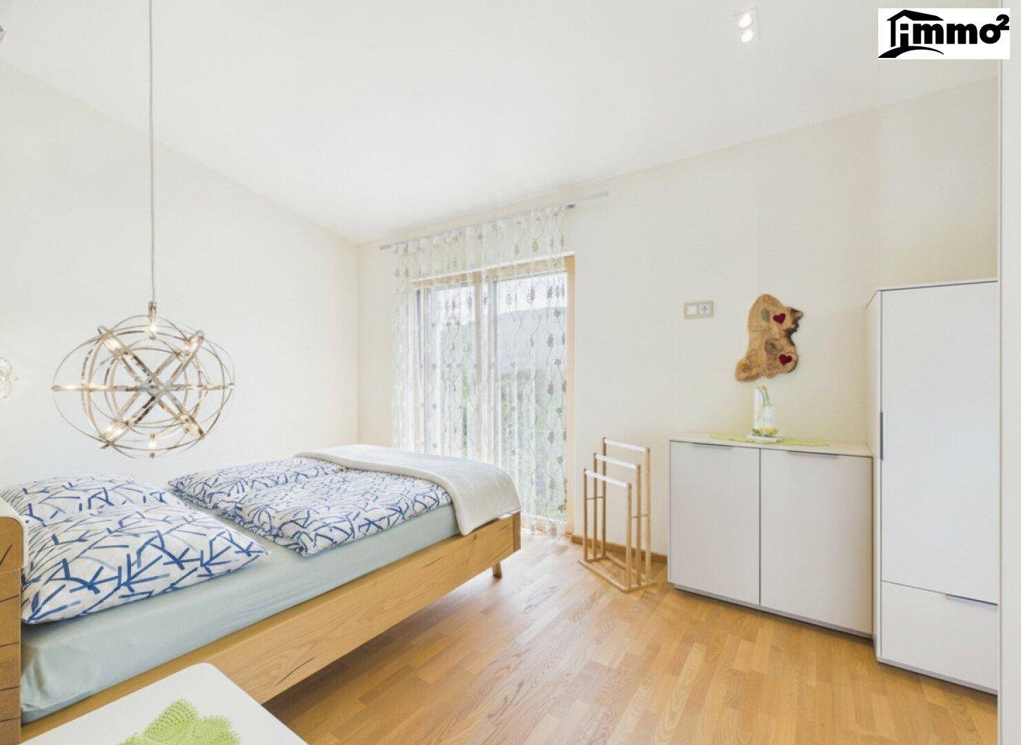 Gemütliches Schlafzimmer mit Holzbett, Parkettboden und Zugang zu einem kleinen Balkon.