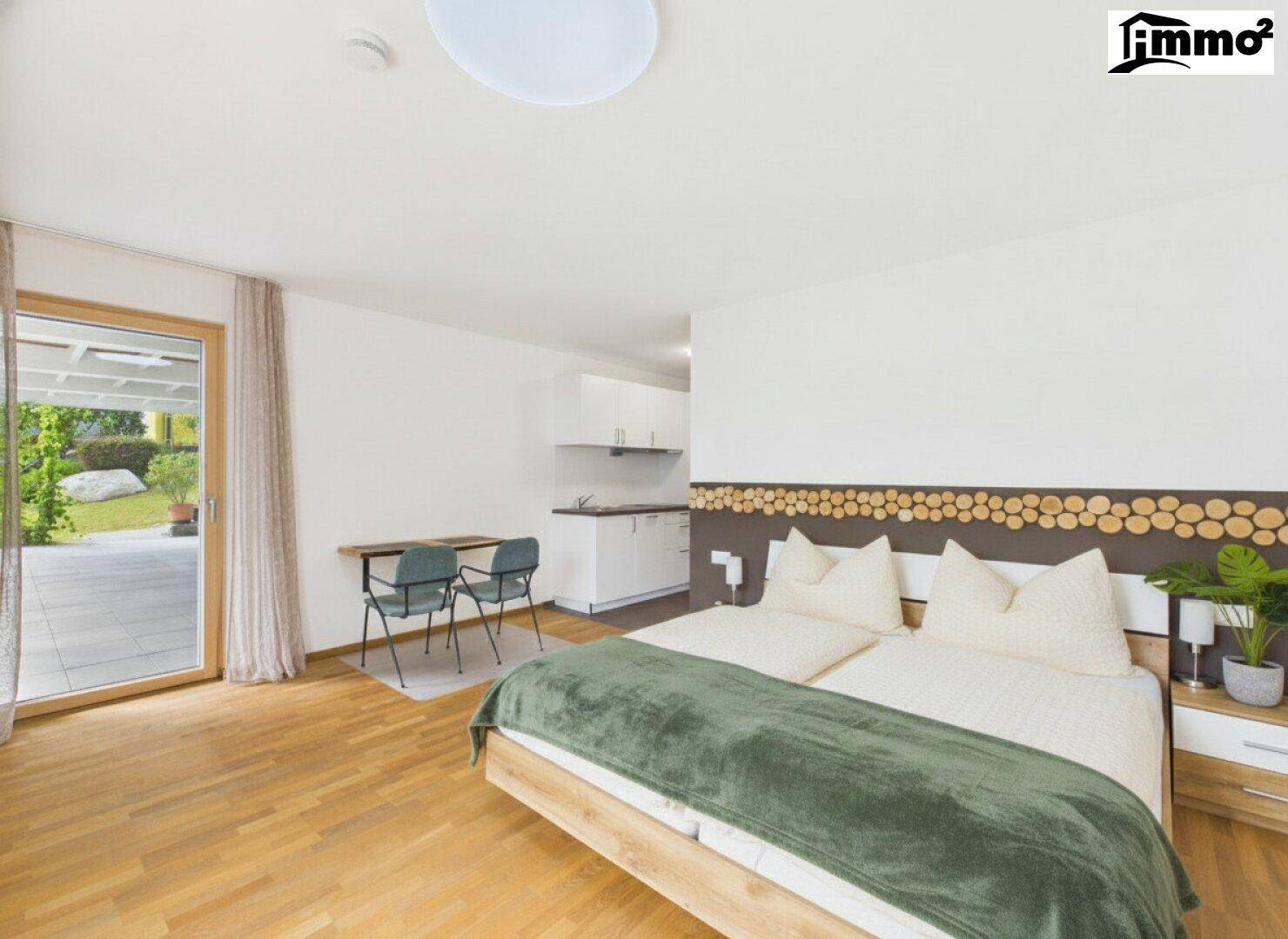 Geräumiges Schlafzimmer mit Holzboden, integrierter Küchenzeile und Zugang zur Terrasse.