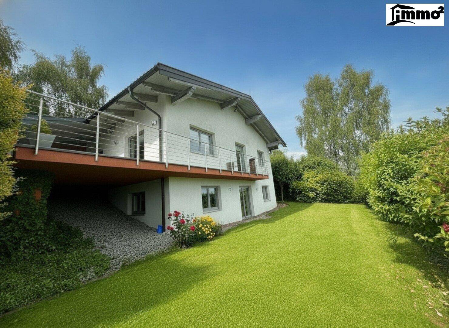 Modernes Einfamilienhaus mit großem grünen Garten, Bäumen und einem Balkon.