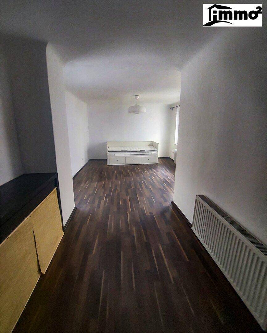Langer Flur mit dunklem Holzboden, der zu einem hellen Raum führt und viel Platz bietet.