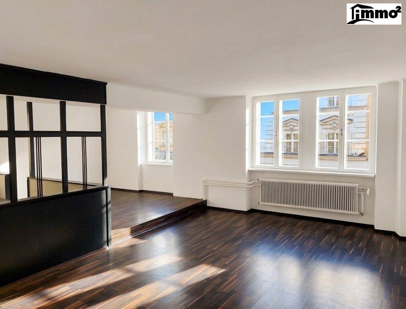 Geräumiges Wohnzimmer mit dunklem Holzboden und großen Fenstern, die einen Blick auf die Stadt bieten.