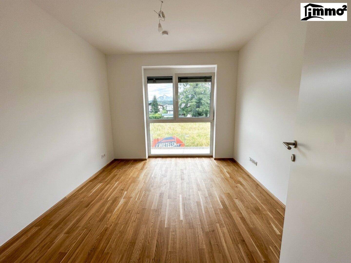 Lichtdurchflutetes Zimmer mit Parkettboden und weitem Blick ins Grüne.