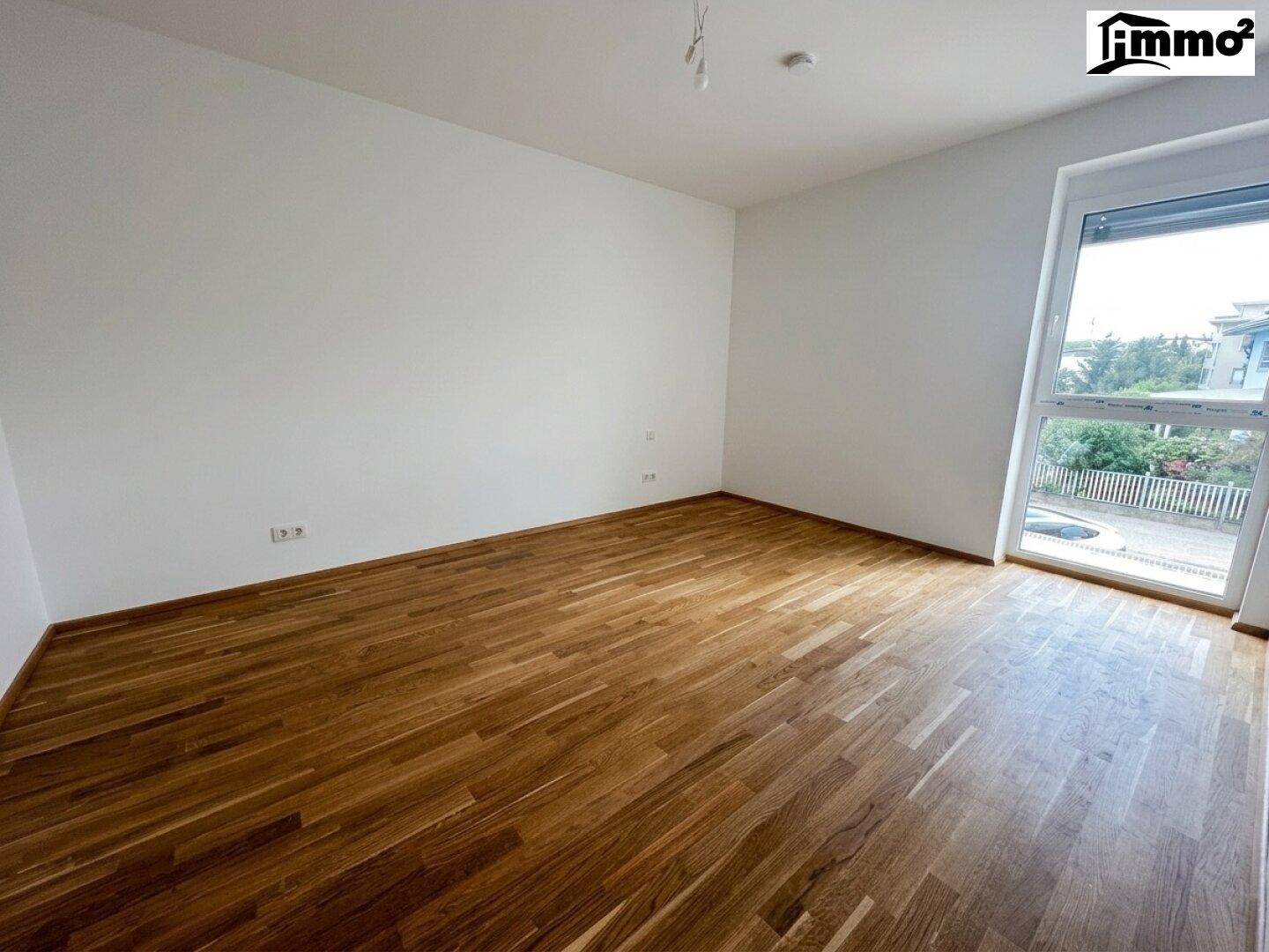 Helles Zimmer mit Parkettboden und großem Fenster, ideal als Schlaf- oder Arbeitszimmer.