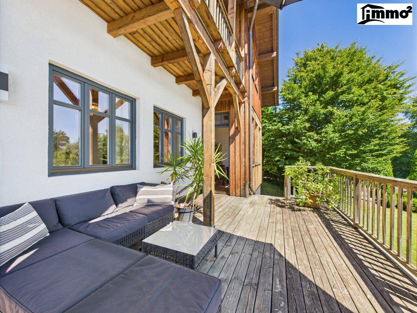 Große Holzterrasse mit Lounge-Möbeln und Blick ins Grüne.