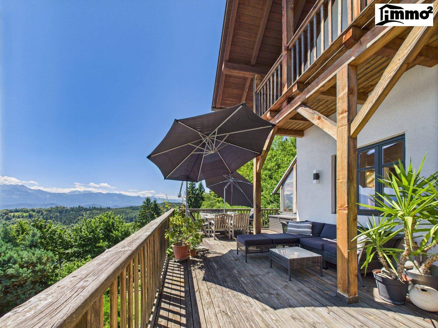 Weitläufige Holzterrasse mit Lounge-Bereich, Sonnenschirmen und Panoramablick.