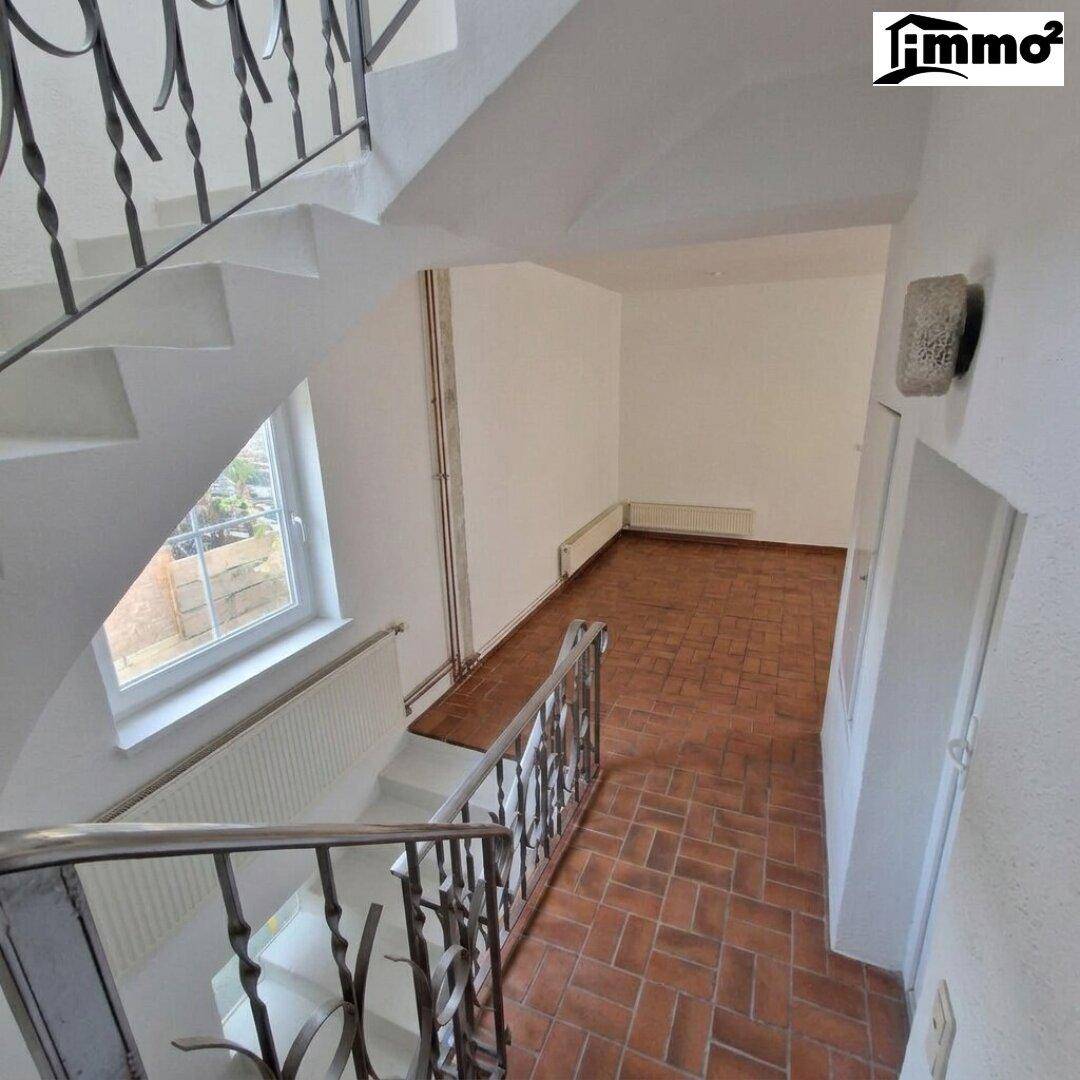 Treppenhaus mit schmiedeeisernem Geländer und Terrakotta-Fliesenboden.